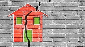 Cracked brick wall with a colored house drawn on it.jpg