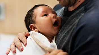 new-born-baby-held-by-man-to-his-chest-sm.jpg
